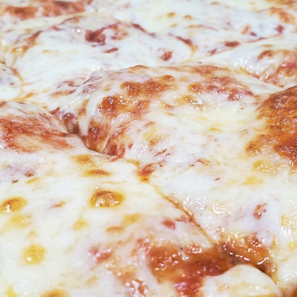 Close-up of a baked dish covered in melted, golden-browned cheese.